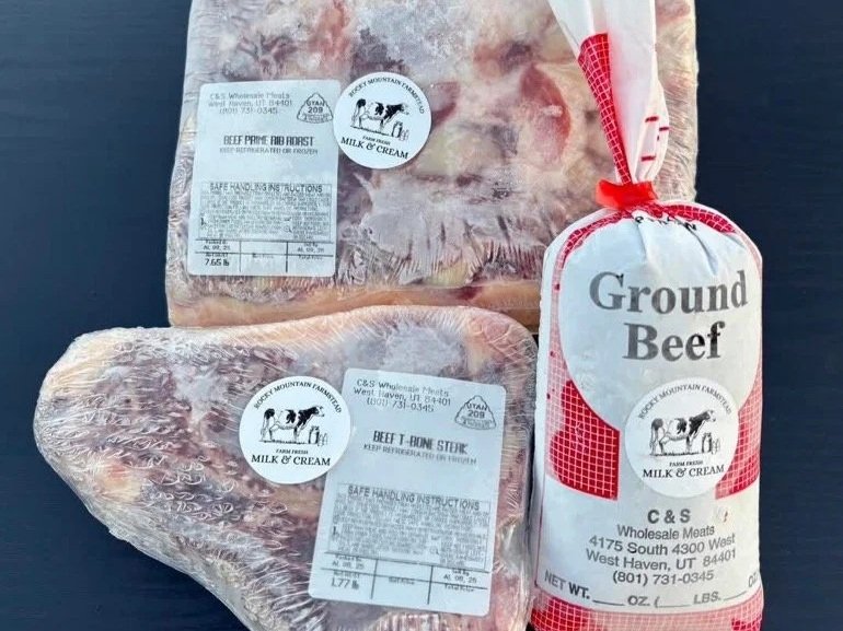 Assorted beef cuts including a beef prime rib roast, a beef T-bone steak, and ground beef, all packaged with labels indicating safe handling instructions and sourced from C&S Wholesale Meats in West Haven, Utah.